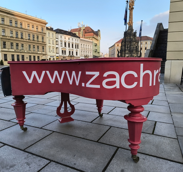 Za červenými piany v ulicích Olomouce stojí filharmonici